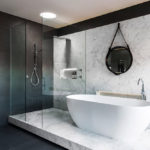 Черно-белая ванная комната с мраморными подиумом и стеновой панелью