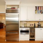Холодильник в интерьере белой кухни угловой.