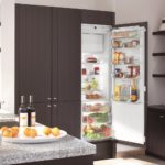 Холодильник в интерьере кухни во встроенном шкафе