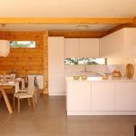 Строгая белая кухня в доме с деревянной отделкой