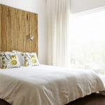 Изголовье кровати из бамбука в спальне с большим окном