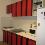 Красный гарнитур с черным декором на бежевой кухне