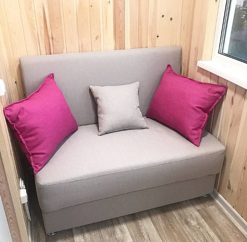 Серый диванчик на балконе с деревянной обивкой
