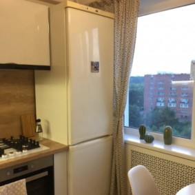Двухкамерный холодильник возле кухонного окна