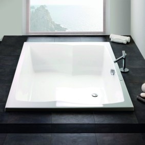 Белая ванна в черном подиуме