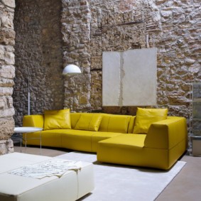 Яркий диван на фоне каменных стен