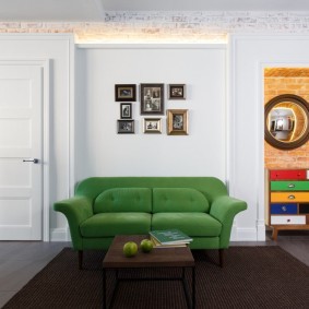 Зеленый диван у белой стены гостиной
