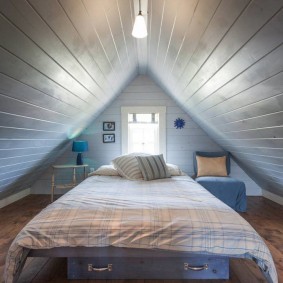 Кровать в маленькой комнате мансарды дачного домика