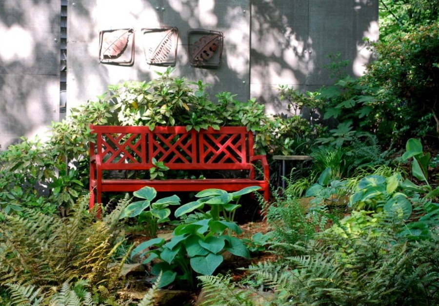 Красная скамейка среди зеленых растений