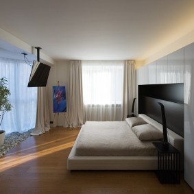 Широкая кровать в спальне стиля минимализма