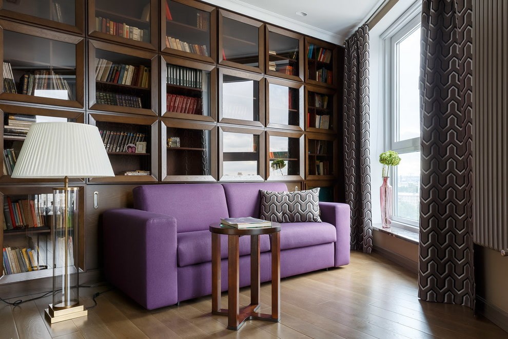Фиолетовый диван в гостиной с домашней библиотекой
