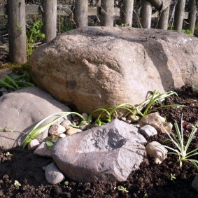Крупные камни у садового забора