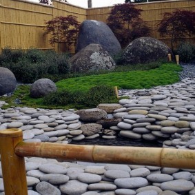 Сад камней на участке с забором из бамбука