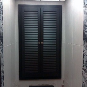 Черные дверки в туалете с кафелем светлого оттенка