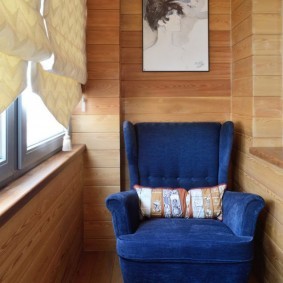 Синее кресло на балконе с деревянной отделкой